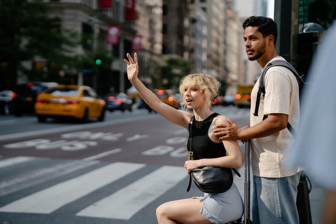 Casal chamando um táxi amarelo em uma avenida de Nova York